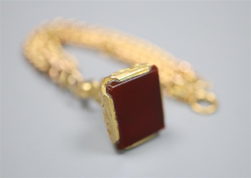 An early 20th century 9ct gold curblink bracelet, hung with a yellow metal overlaid carnelian set fob seal,